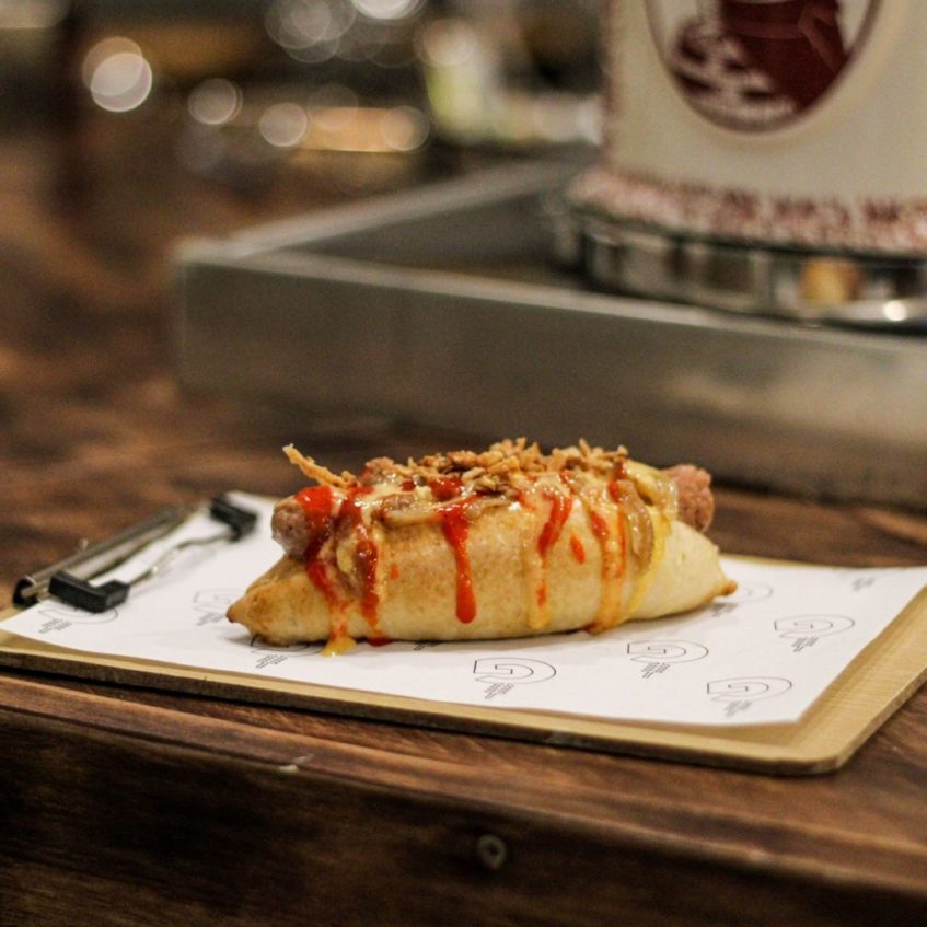 El 'hotdog de aquí' en pan panetti artesano y chistorra al vino con cebolla en dos texturas. Foto cedida por el establecimiento